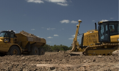 two CAT trucks on dirt site